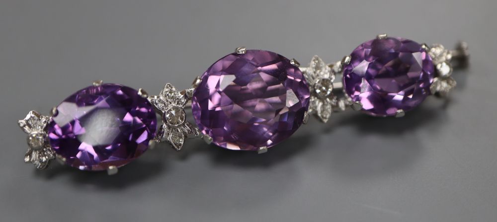 A modern white metal, three stone oval cut amethyst and diamond chip set bar brooch, 55mm, gross 11.1 grams.